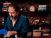 a man in a blue shirt sits at a desk with a woman in a striped jacket standing behind him