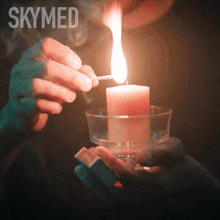a person lighting a candle in a glass with skymed written on the bottom right