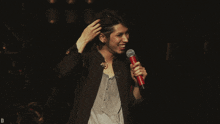 a man in a black jacket is holding a microphone and smiling