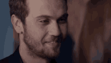 a close up of a man 's face with a beard smiling