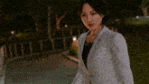 a woman in a white suit is standing in a park
