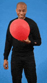 a man in a black sweater is holding a large red balloon