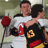 a hockey player with the number 43 on his back hugging another player
