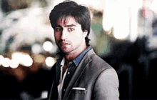 a man in a suit and a denim shirt is looking at the camera .