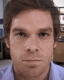 a close up of a man 's face with a beard in a blue shirt .