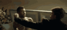 a man without a shirt is being punched in the face by another man .