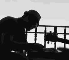 a silhouette of a man playing a guitar in front of a railing