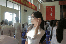 a woman adjusts her hair in front of a sign that says ngày mai tập nghề