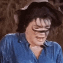 a man in a blue shirt and cowboy hat is crying .