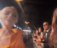 a woman in a yellow dress is standing in front of a crowd of people