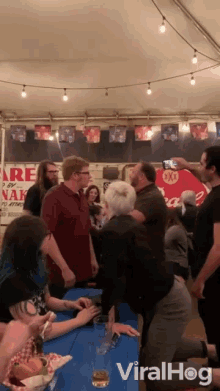 a group of people are gathered under a tent with a sign that says fire naked