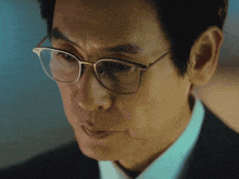 a close up of a man wearing glasses and a black suit