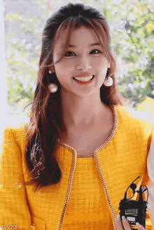 a woman in a yellow jacket is smiling and holding a radio