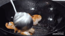 a pan of shrimp is being stirred with a ladle and the words made in animatica are visible