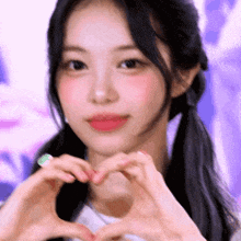 a young woman is making a heart with her hands .