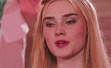 a close up of a woman 's face with long blonde hair and red lips .
