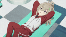 a girl in a red and white jacket is laying on a green mat