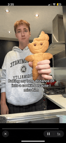 a man in a gray hoodie is holding a gingerbread man