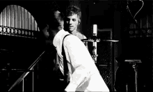 a man is playing a guitar in a black and white photo while another man stands behind him .
