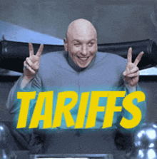 a bald man gives a peace sign in front of a sign that says tariffs