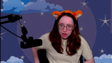 a woman wearing glasses and a tiger ear headband is sitting in front of a microphone