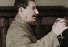 a man with a mustache is holding a wine glass