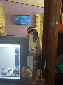 a woman taking a selfie in front of a mirror with a tv behind her that says netflix