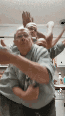 a man in a blue shirt is dancing in a kitchen with the hashtag tiktok
