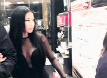 a woman in a black dress with a plunging neckline is standing next to a man .