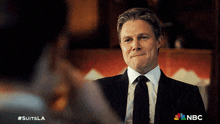 a man in a suit and tie is looking at another man in a suit and tie