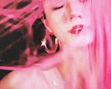 a close up of a woman 's face with pink hair wearing hoop earrings