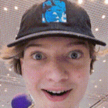 a close up of a person wearing a baseball cap with a blue logo on it .