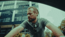 a man wearing sunglasses and a gray shirt is sitting in a car