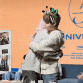 a woman wearing a giraffe headband hugging another woman