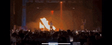 a crowd of people watching a concert with a fire coming out of the ceiling