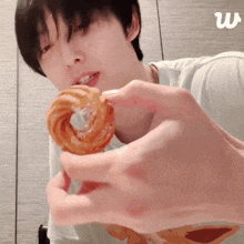 a person holding a donut in their hand with the letter w in the corner
