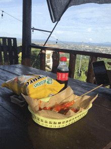 a bottle of coca cola sits on a table next to a bag of regent chips