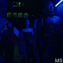 a group of people are walking down a dark hallway with the letters ms on the bottom right