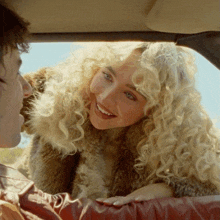 a woman in a fur coat is smiling at a man
