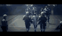 a group of soldiers are walking down a street carrying a man