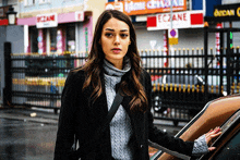 a woman stands in front of a store that says eczane on it