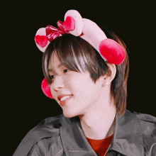 a man wearing a pink headband with hearts on it smiles