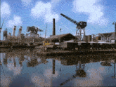 a dock with a few boats and a crane and a reflection of a building in the water