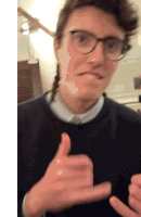 a blurry photo of a man wearing glasses giving a thumbs up sign