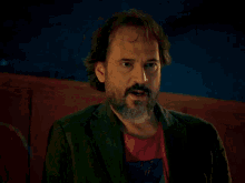a woman in a green jacket stands next to a man in a dark room