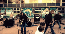 a band is playing in front of a wall with a mural of animals on it