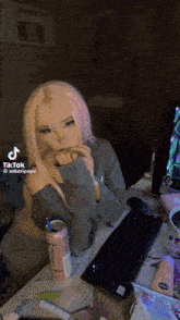 a girl with pink hair is sitting at a desk with a keyboard and a monster energy drink .