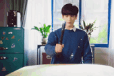 a young man in a blue sweater is holding a sword in his hand .