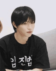 a young man wearing a black t-shirt with korean writing on it