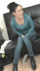a woman in a blue shirt is sitting on a couch